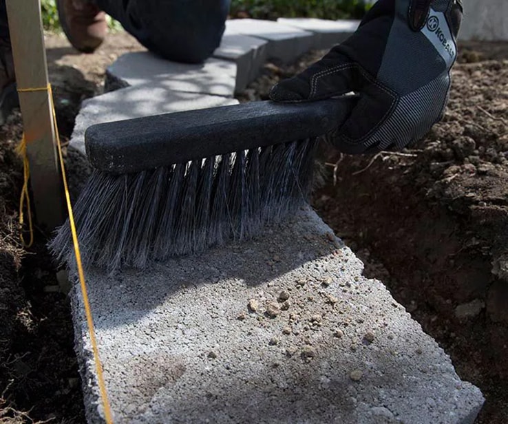 Personne utilisant un balai pour nettoyer un bloc de béton