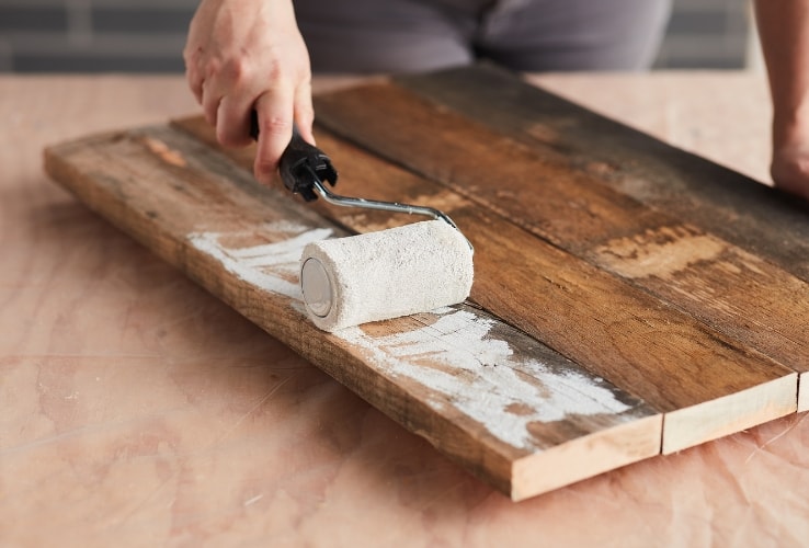 Person painting wooden planks