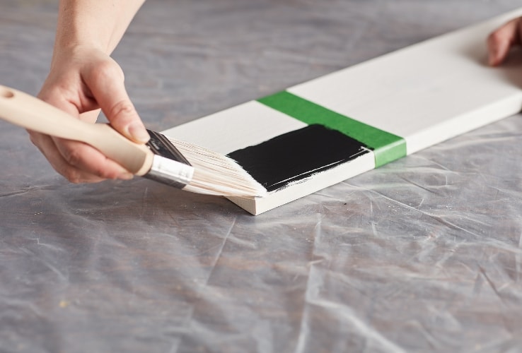 Person painting on a white wooden plank