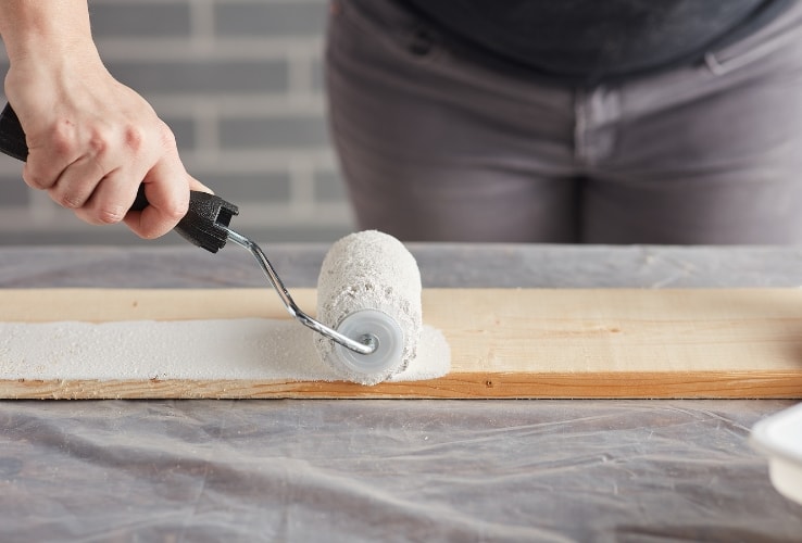 Person painting a plank white