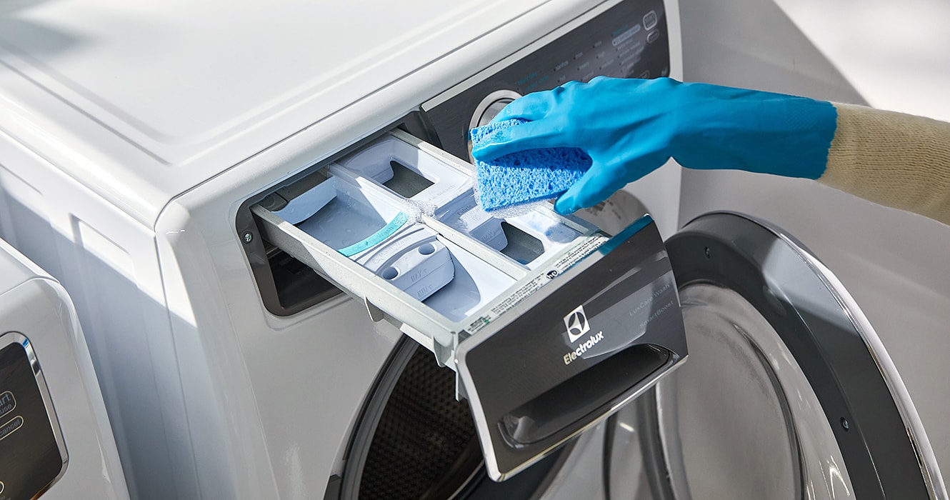 Person cleaning a washer soap dispenser