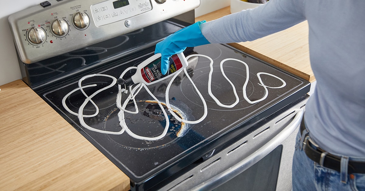 Person cleaning a glass stovetop