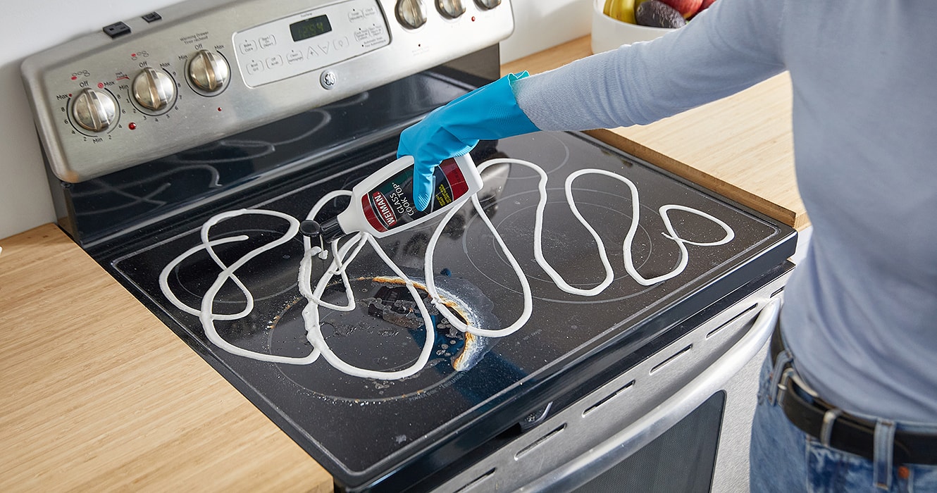 Personne versant une crème nettoyante sur une plaque de cuisson