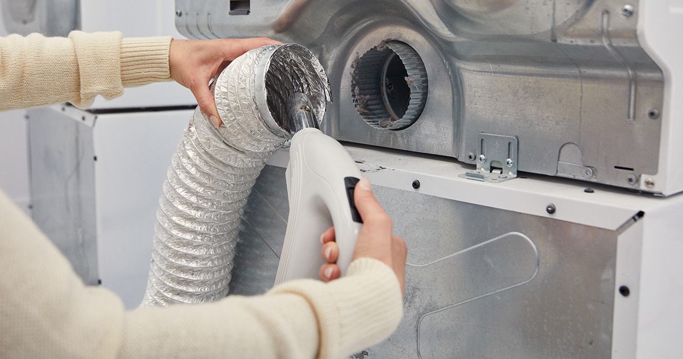 Person vacuuming a dryer vent