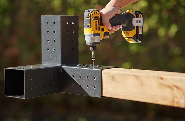 Person installing TOJA GRID hardware on a wooden post