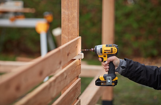 Person installing wood slats to create a privacy wall