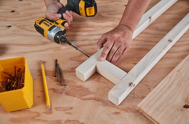 Personne qui visse des planches de bois ensemble