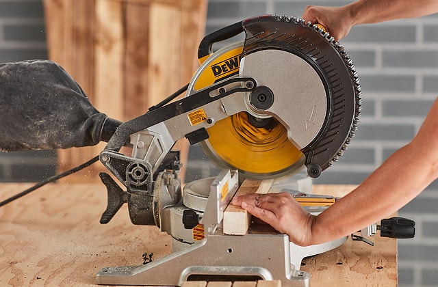 Person cutting wood with a mitre saw