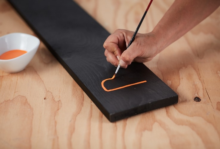 Person painting a wooden plank