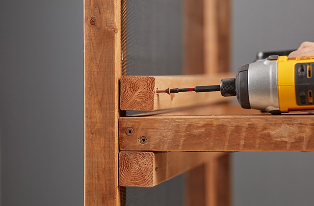 Person adding an upper drawer support to a wooden structure