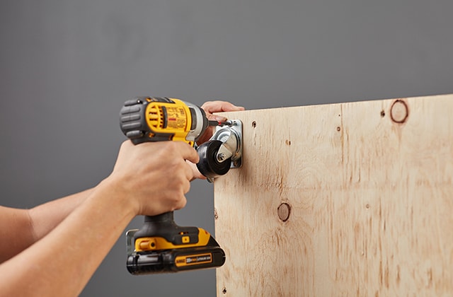 Person securing casters to a wooden structure