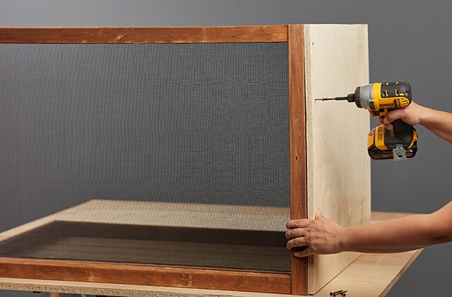 Person securing wooden frames to a plywood base