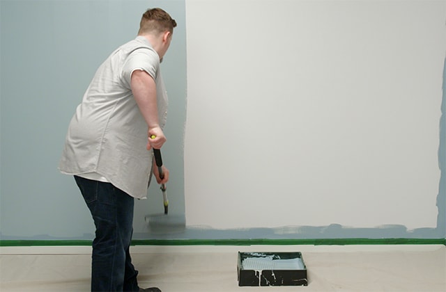 Homme peinturant un mur en bleu