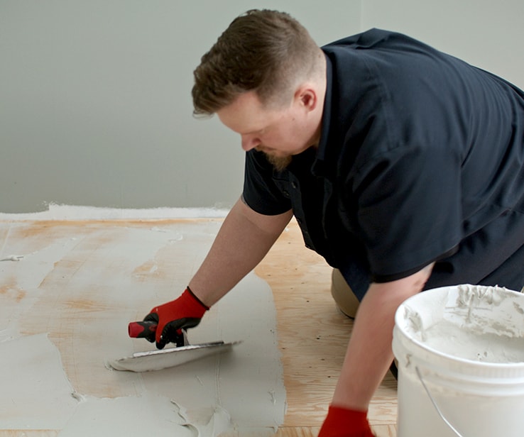 Person spreading mortar on a subfloor