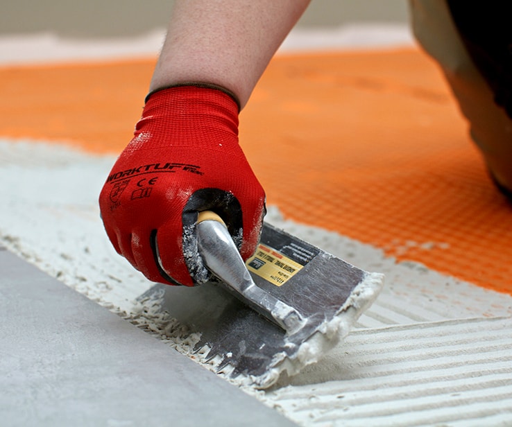 Personne appliquant du ciment-colle sur un plancher