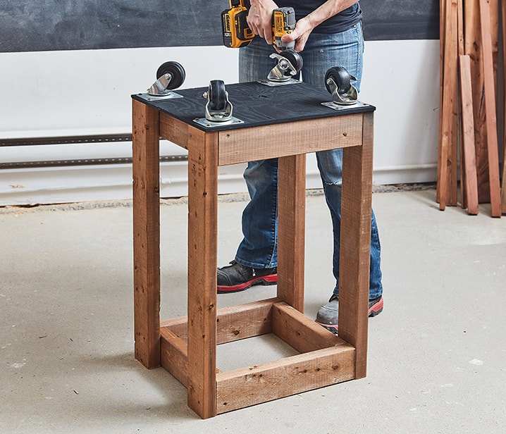 Femme vissant des roulettes sur une structure en bois