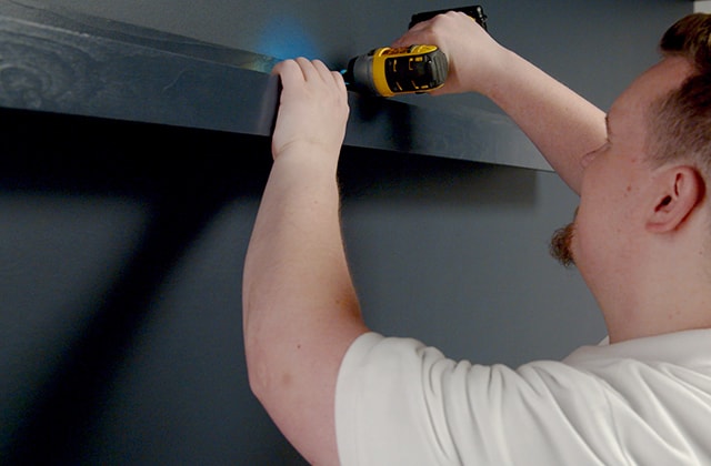 Homme vissant une tablette dans un mur