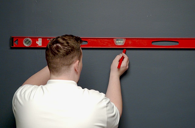 Homme traçant une ligne sur un mur