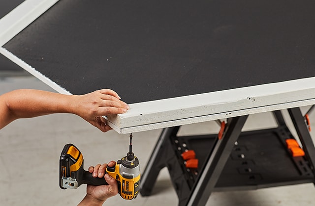 Person assembling a wooden chalkboard