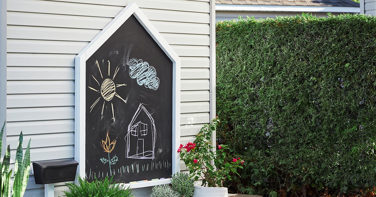 Tableau noir extérieur en forme de maison dans une cour arrière