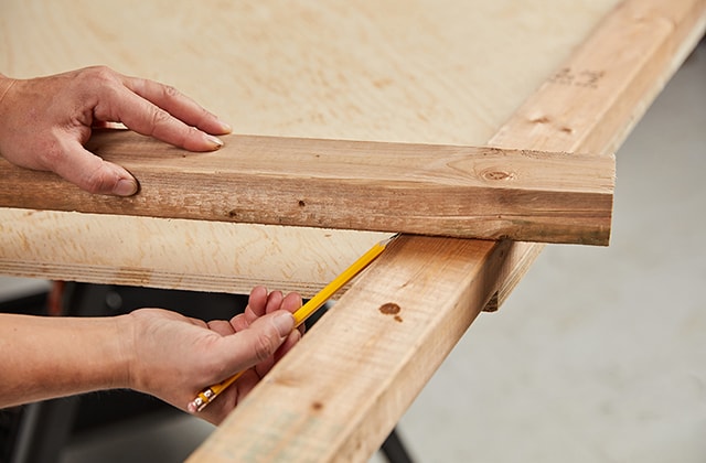 Person tracing an angle to cut on a piece of wood