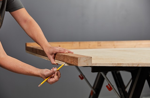 Personne traçant un angle de coupe sur un morceau de bois