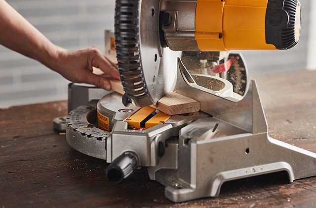 Person cutting wood with a mitre saw