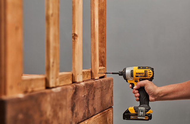 Personne fixant des planches à la verticale sur une structure