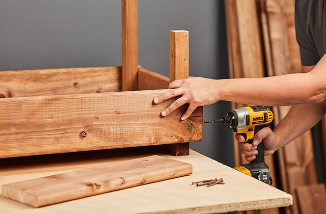 Person adding a row of planks on a planter box