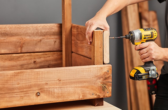 Person adding a second row of planks on a planter box