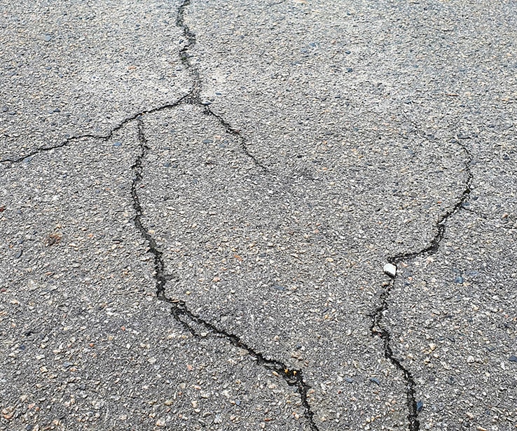 Several cracks on an asphalt driveway surface