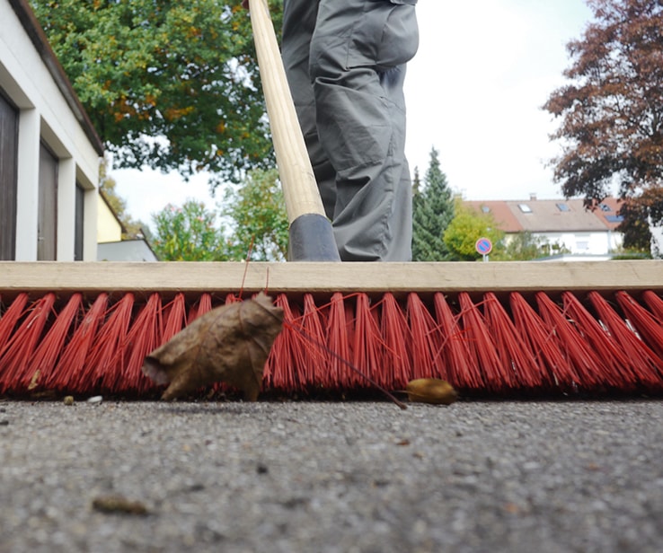 Person sweeping a driveway to remove debris