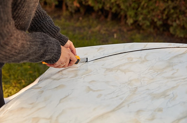 Personne appliquant de la pellicule autocollante sur une table de patio