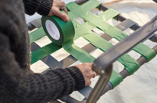 Person applying masking tape to patio chairs