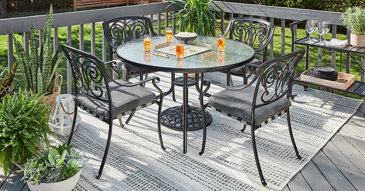 Patio avec des meubles de jardin en métal et un tapis extérieur