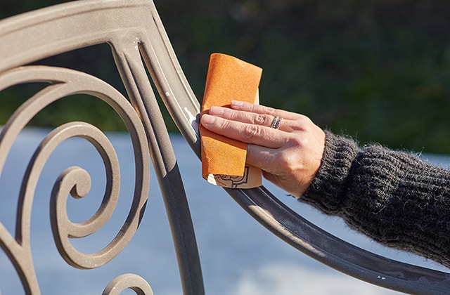 Person sanding a metal patio chair