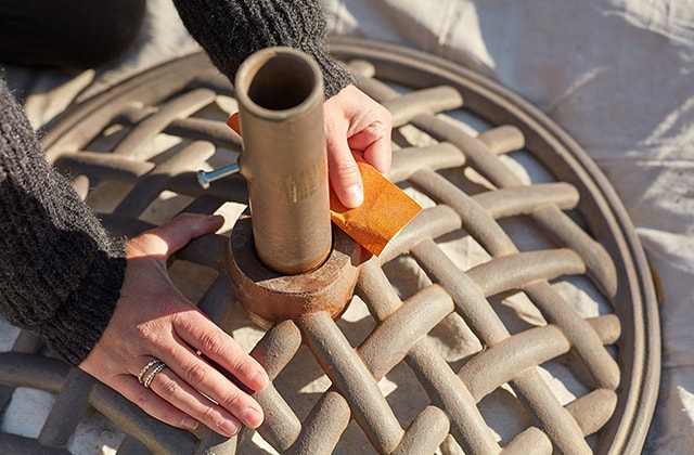 Person sanding a rusted umbrella support