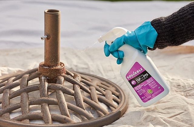 Person spraying cleaner on an umbrella support