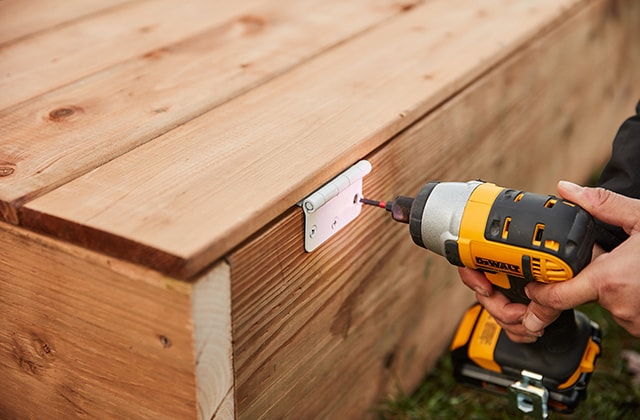 Personne fixant des charnières sur une porte en bois