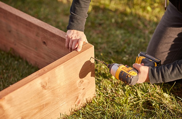 Person assembling a wood structure with a drill