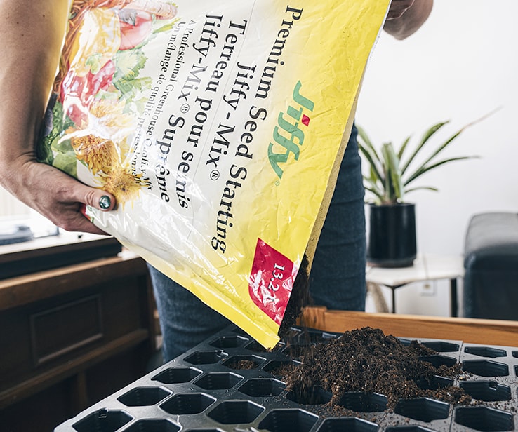 Woman adding soil to a seedling tray