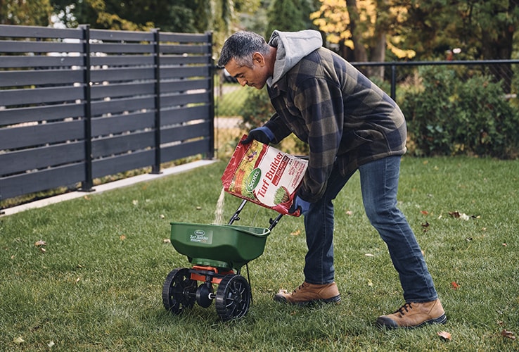 Man pouring lawn fertilizer into a spreader