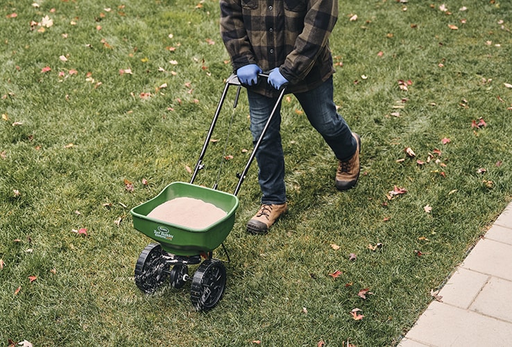 Man using a spreader to fertilize a lawn