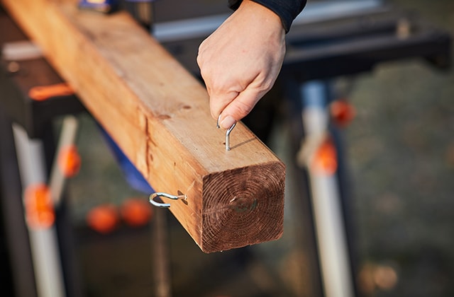 Person installing screw hooks on a wooden post