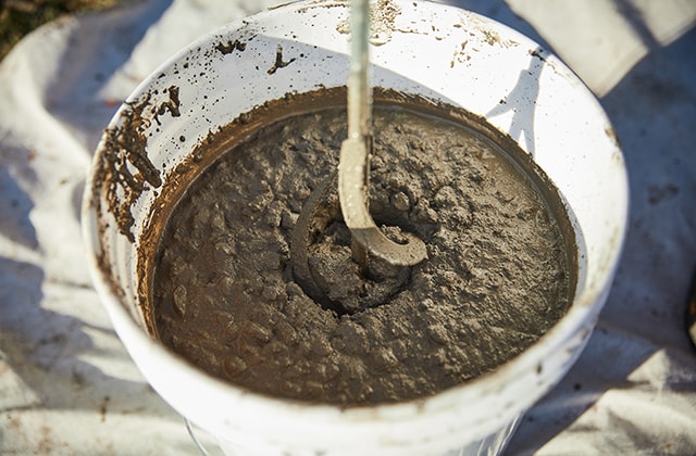 Person mixing concrete with a drill and mixer