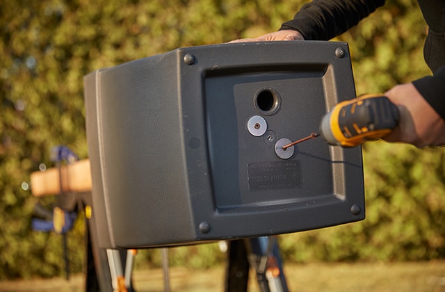 Person using a drill to secure a post in a planter