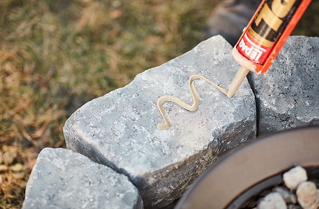 Person applying construction adhesive to a cinder block