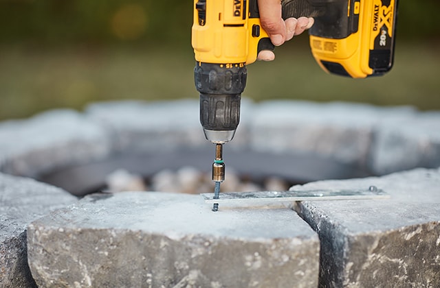 Person joining two cinderblocks with a steel plate