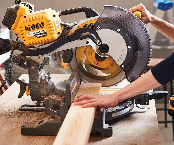 Person cutting wood with a mitre saw