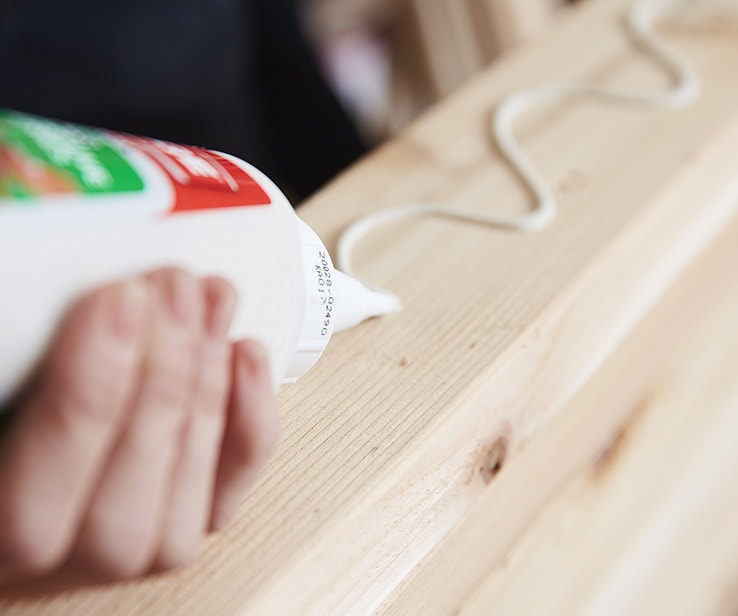 Person apply glue on a piece of wood